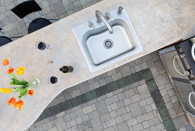 Outdoor kitchen sink with bar stools and a bbq.